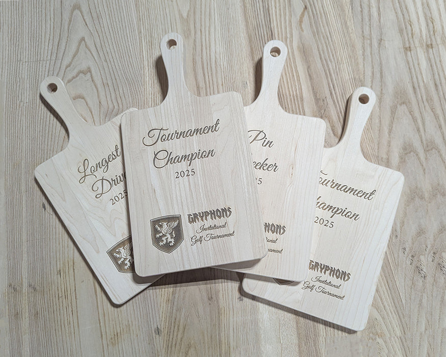 Four wooden cutting boards with engraved text and logos on a wooden surface