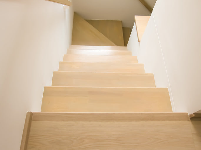 Wooden staircase with a light finish in a well-lit interior setting